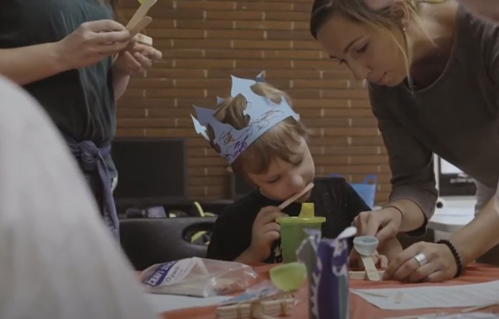 Students help a child complete a craft.