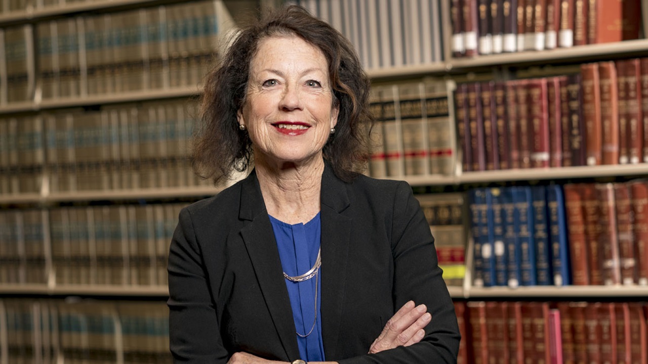 Christine Hutton standing in the law library, smiling at the camera. Christine Hutton standing in the law library, smiling at the camera.