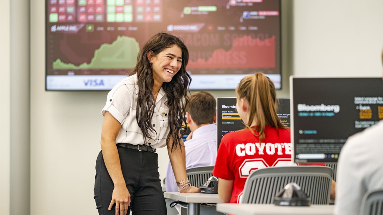A USD student stands over another, looking onto a computer screen with Bloomberg technology. They are in the Ellis Lab. A USD student stands over another, looking onto a computer screen with Bloomberg technology. They are in the Ellis Lab.