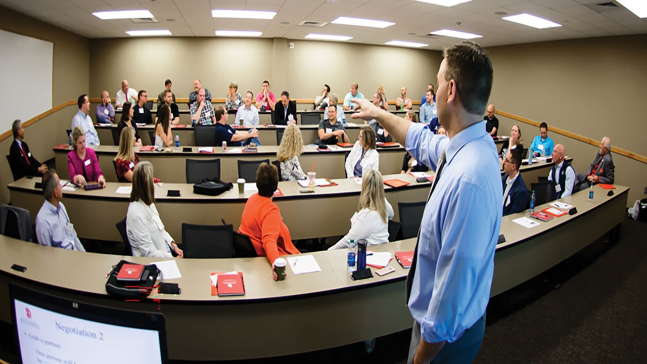 An executive education instructor talks to a big class of students. An executive education instructor talks to a big class of students.