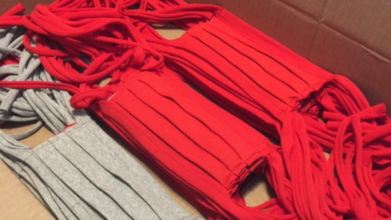 Red and gray cloth face masks stacked on a table.