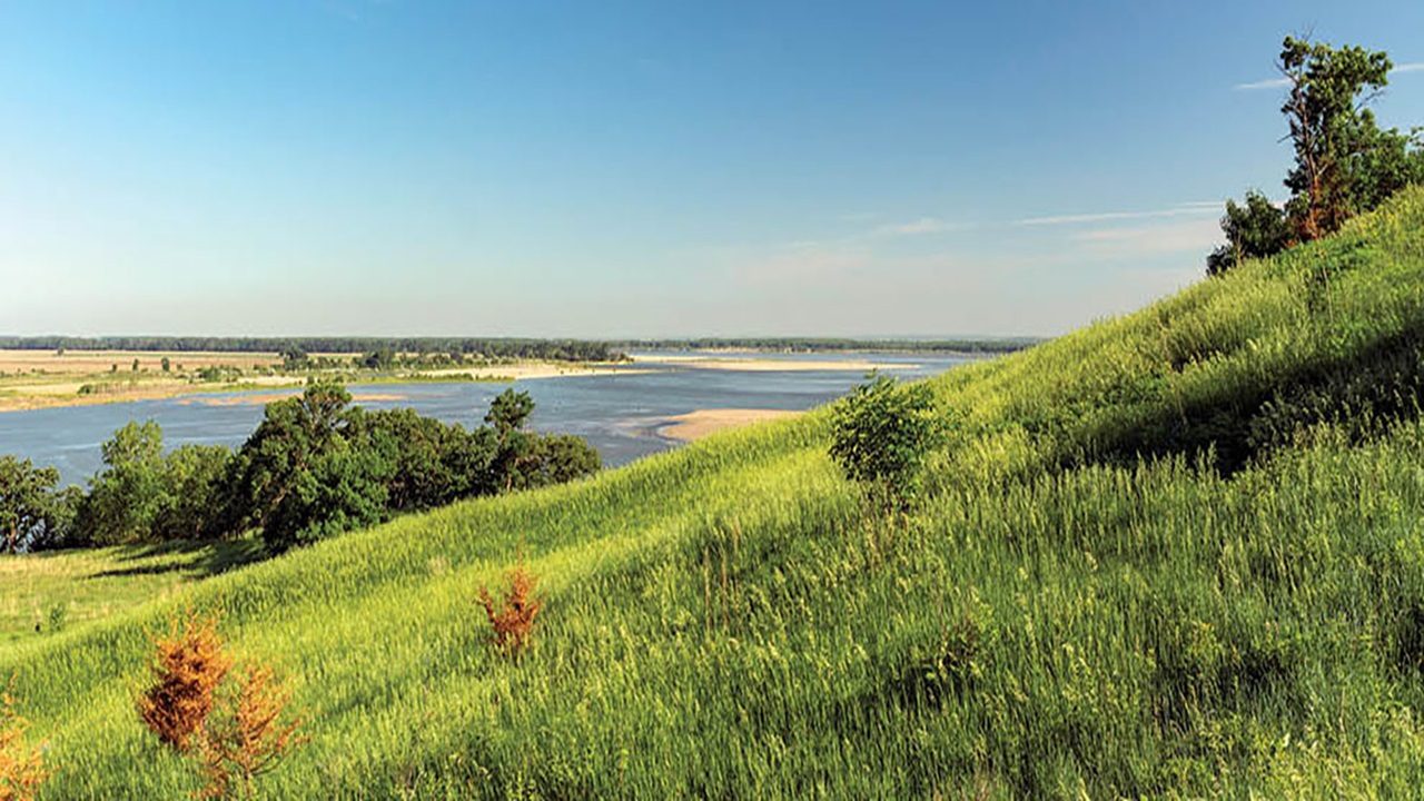 A view of the Missouri River. The grass is green and the skies are blue. A view of the Missouri River. The grass is green and the skies are blue.