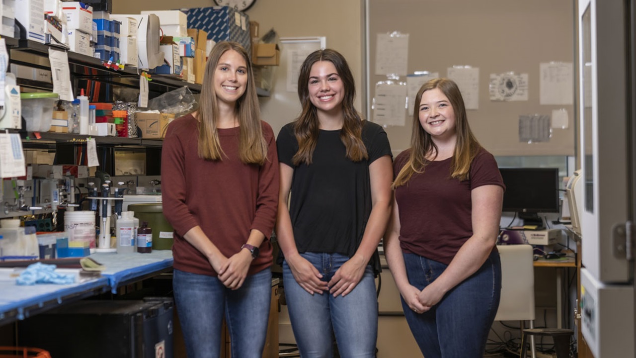 Morgan Eikanger, Emily Eisenbraun and Kylie Christiansen standing together in a lab Morgan Eikanger, Emily Eisenbraun and Kylie Christiansen standing together in a lab