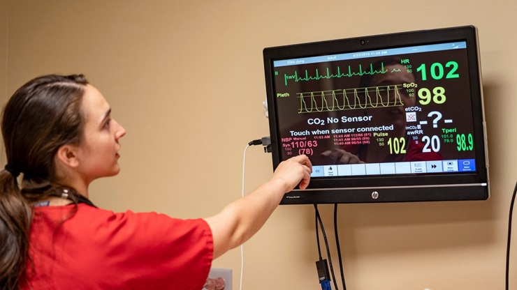 A nursing student looks at a medical display screen.