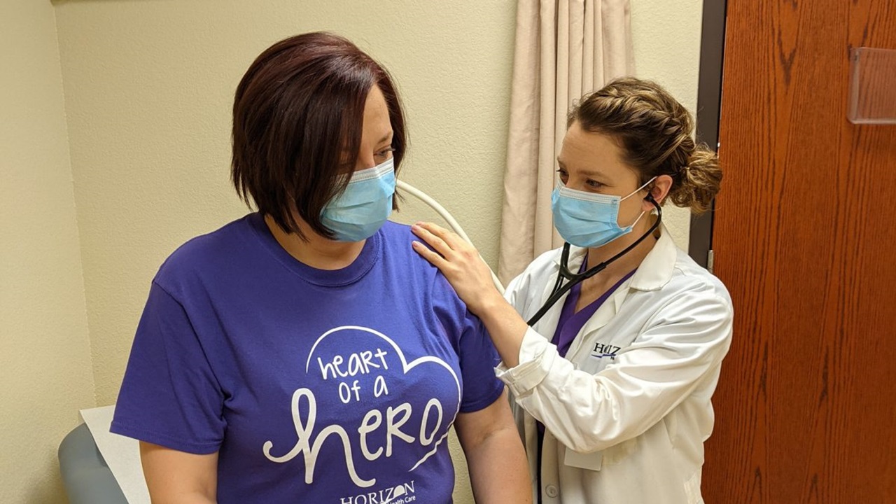 A physician assistant administers a shot to a patient.
