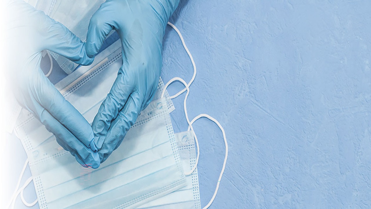 A pair of hands wearing blue medical gloves in a shape of heart. A pair of hands wearing blue medical gloves in a shape of heart.