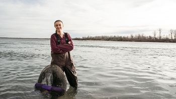 Ruby Hawks standing in the Missouri River with a net.