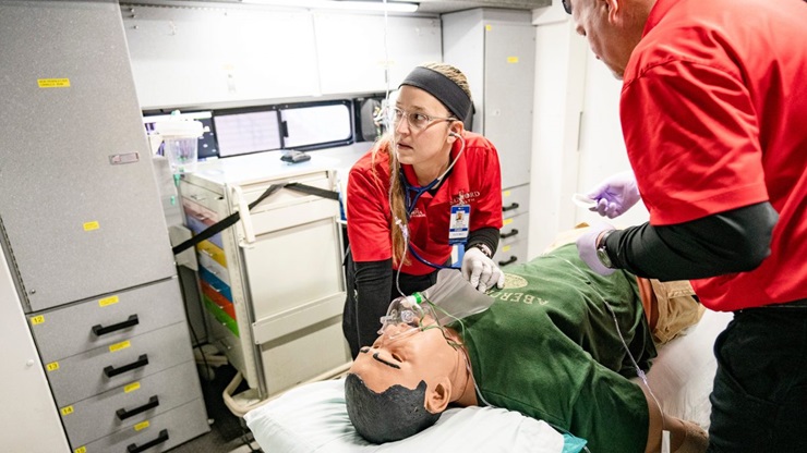 Nursing students check the vitals of a training manikin.