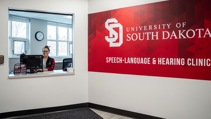 A student-worker sits at the front desk at the Speech-Language and Hearing Clinic