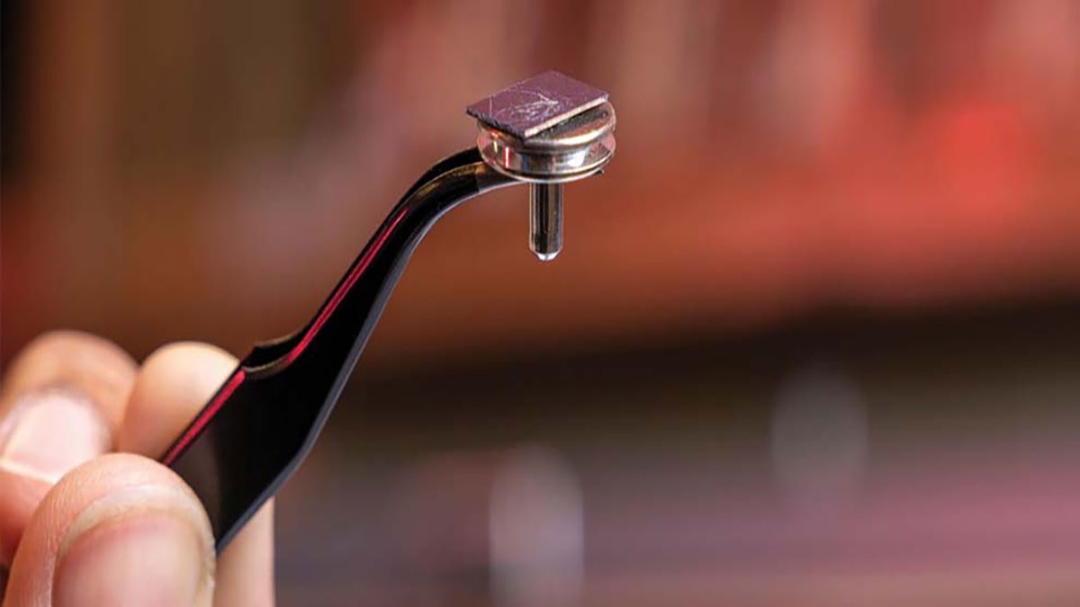 A hand holds a tiny tool with tweezers.