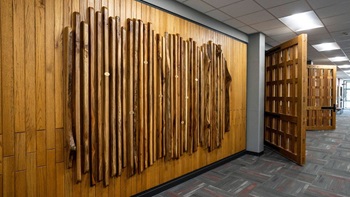 A picture of the College of Fine Arts Honor Wall. The wall is wood with with vertical wooden planks.
