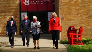 President Sheila K. Gestring and three other individuals walk out of the Knudson School of Law.