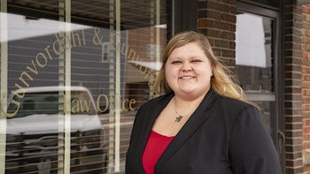 Rachelle Norberg stands and smiles in front of a law office.