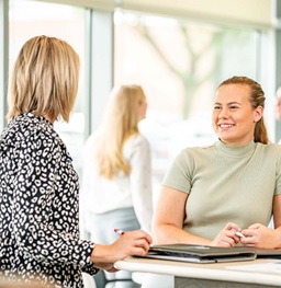 A student talking to a teacher in the Beacom School of Business.