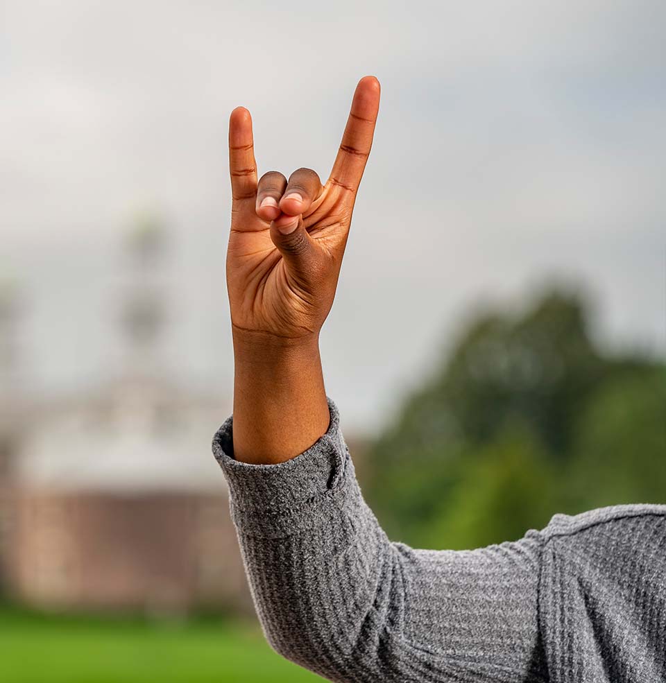 A student holding a Yote hand symbol.