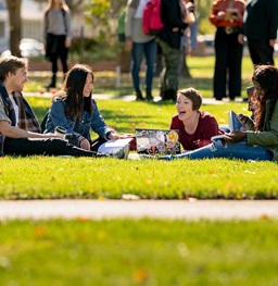 A group of students laying on the campus lawn and laughing.