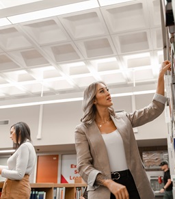 A law student pulling a book down from a shelf.