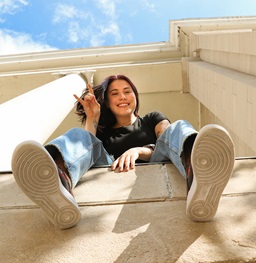 A student sitting on a ledge looking down and smiling.