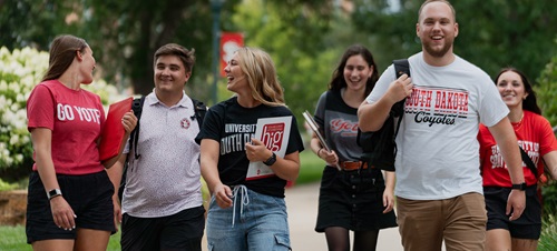 USD students smiling and walking on campus together.