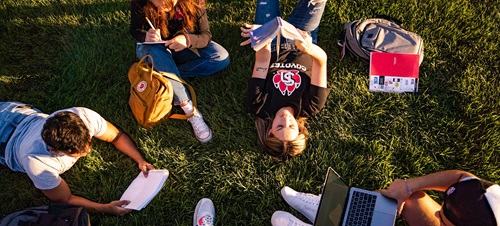 Students sitting on the MUC lawn reading and talking.