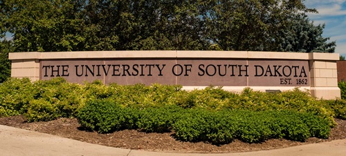 University of South Dakota Sign Behind Shrubs