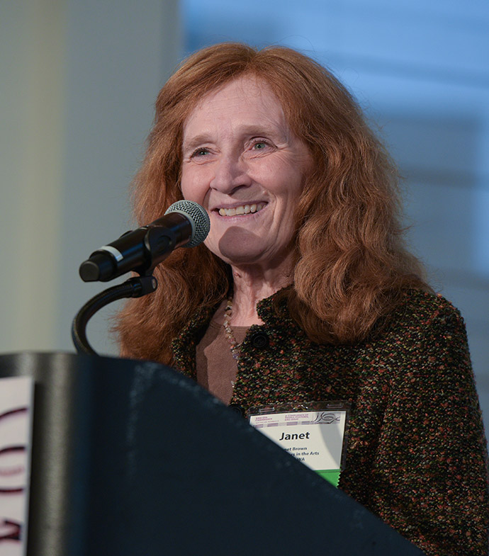Success story Janet Brown speaking into a microphone at a podium.