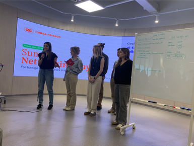 Students from the Beacom School of Business stand in a conference room presenting to business personnel.