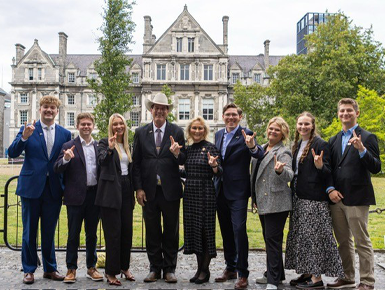 USD students stand with South Dakota Governor Larry Rhoden, posing with the "Yotes" hand signal.