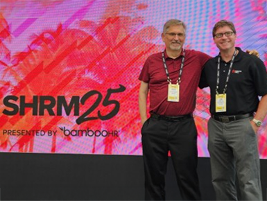 USD faculty members stand in front of a screen that displays the 2025 Society for Human Resource Management branding.