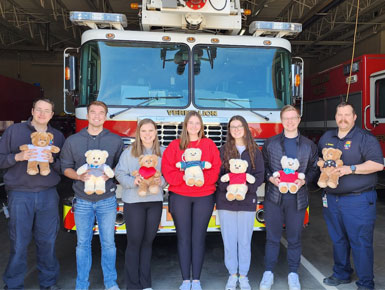 Build-a-Bear participants standing in front of firetruck with stuffed bears