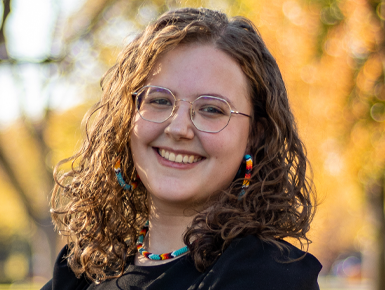 Rachel Overstreet smiling with fall trees behind her.
