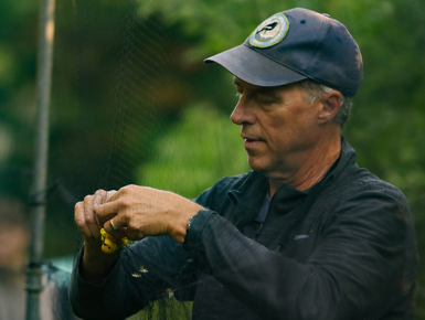 David Swanson stands in a wooded area and removes a bird from a net for research purposes.