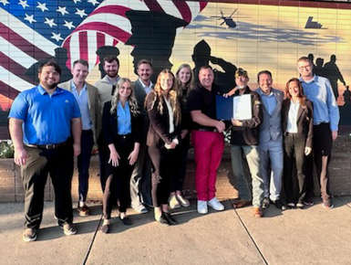 Law students stand together for a photo in front of a brick wall with a mural of an American flag on it.