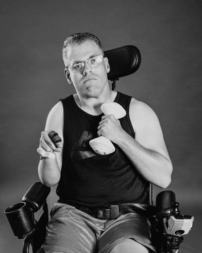 A person in a wheelchair holds up a dumbbell weight.