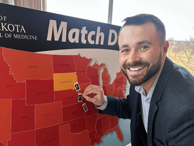Cole Tessendorf, SSOM student, places his match sticker on a map of the United States.