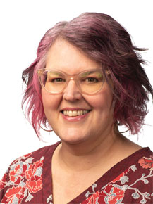 Mary Payton Zajicek posing for headshot in front of white wall