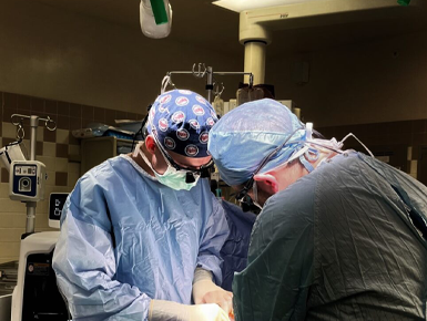 Two medical professional focused on performing surgery in an operating room. 