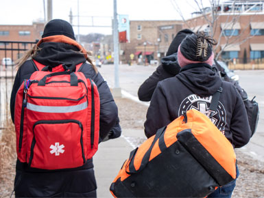 Members of the Midwest Street Medicine Program walk down the streets of Sioux Falls, carrying their backpacks of medical equipment on their backs.