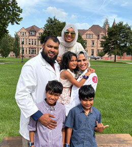 Sadaf Cassim, dressed in her white coat, stands with her husband and children on the USD campus.