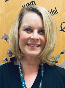 Anna Mortenson posing for headshot in front of yellow wall with writing on it