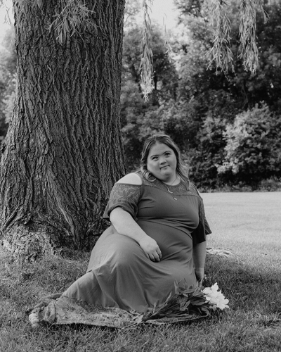 A person sits under a tree and smiles.