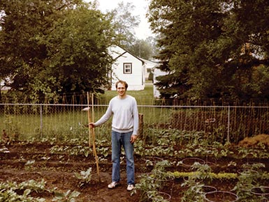 Photograph of Melvin W. Thomas standing in a garden holding a hoe tool.