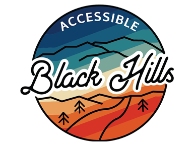 A round logo that says Accessible Black Hills. The top of the circle is dark blue with a gradient of greens and yellows into orange at the bottom.