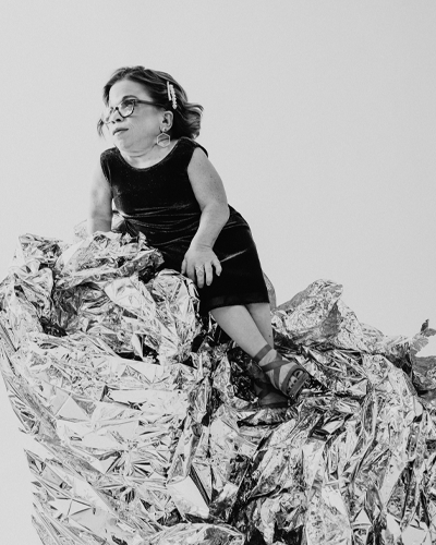 A person sits on a platform that looks like crumbled tinfoil. They gaze off to the left of the image.