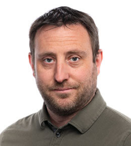 Lee Baugh looks at the camera and smiles. He is wearing a green polo shirt.