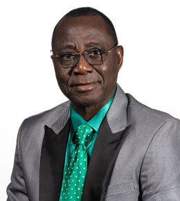 Mejai Avoseh smiles as he poses for his professional photo. He is wearing a gray suit with a bright, aqua-blue undershirt and polka dot tie.