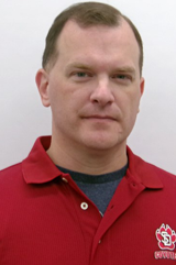 A headshot of Christopher Strunk. He is wearing a red USD polo. 
