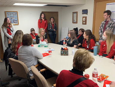 A group of 15 people sit around a table and discuss. 