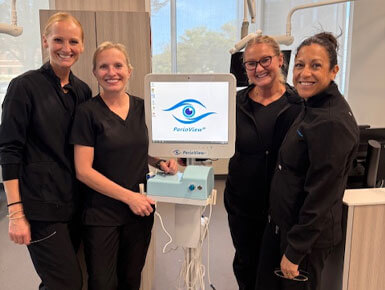 Students in black attire stand next to the new PerioView, with its screen illuminated with the PerioView logo and name in blue on a white background.