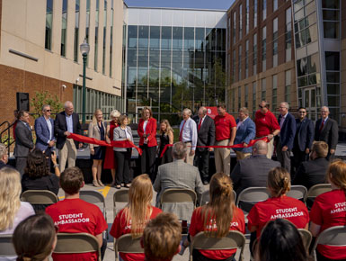 At the Center for Health Education, USD leaders cut a red ribbon with large scissors, marking the official opening of the building.